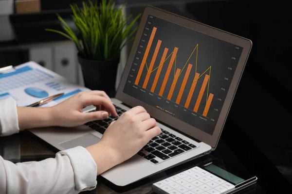 programmer works on laptop with an empty screen in stylish office. Hands economist close-up typing on laptop computer in modern office, analyzing commercial information on calculator. White hands freelancer typing on keyboard on dark glossy table